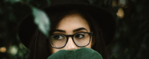 Girl With Glasses Covering Mouth With Leaf