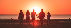 family of five walking on the beach at sunset